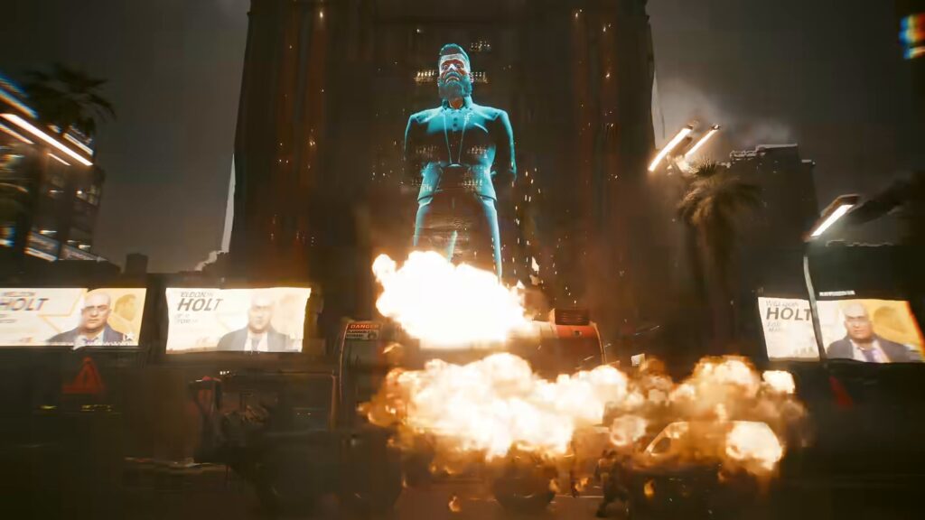 Holograma gigante azul de Richard Night, o fundador de Night City, sobre uma rua com outdoors e uma explosão, em cena do vídeo oficial da atualização 2.5 de Cyberpunk 2077