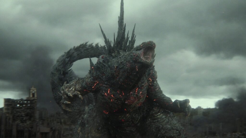 Godzilla, com rachaduras vermelhas brilhando no corpo, ruge diante de uma cidade em ruínas em Godzilla Minus Zero