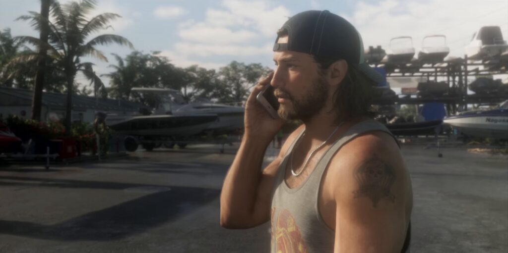 Cena oficial do trailer de lançamento de GTA 6: Jason Duval, de boné virado para trás e regata, atende o celular no pátio da Brian's Marina, com barcos ao fundo