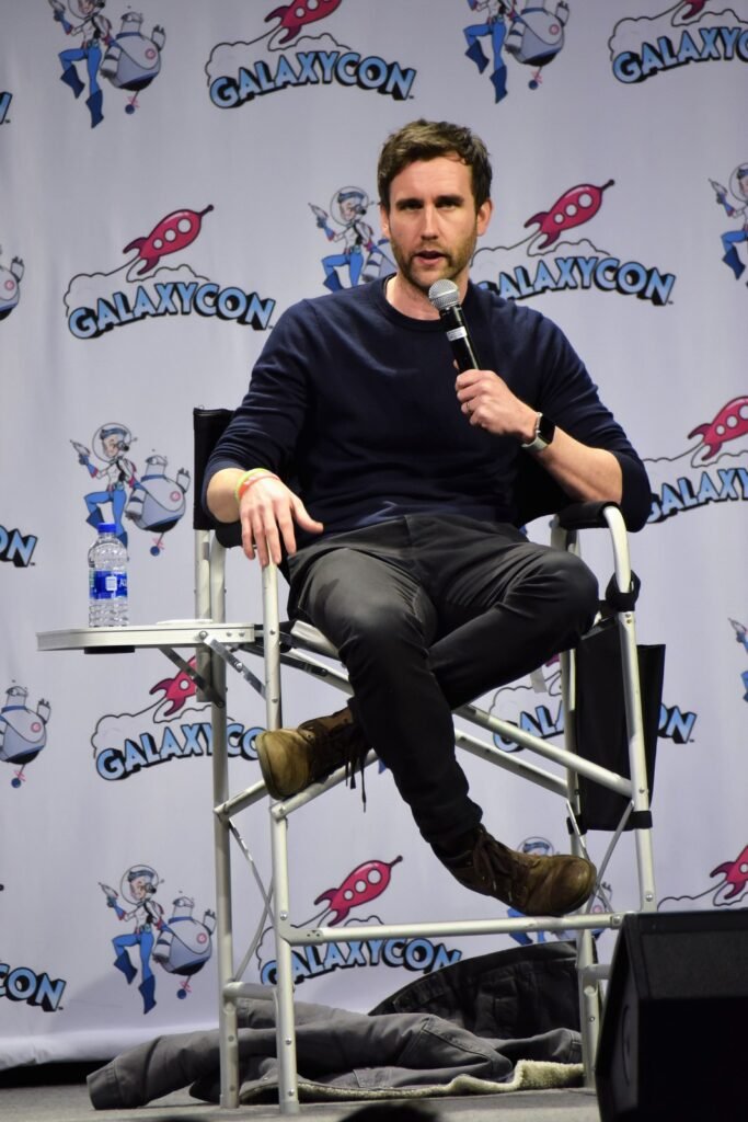 Matthew Lewis sentado com microfone num painel de perguntas e respostas sobre Harry Potter em 2020