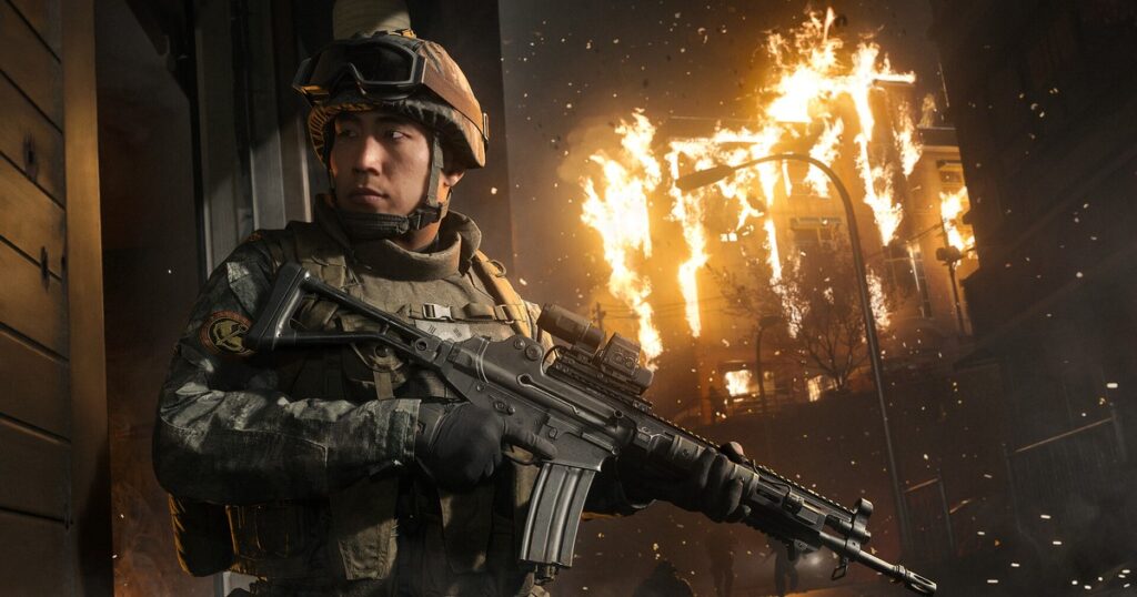 Soldado sul-coreano com fuzil diante de um prédio em chamas em cena oficial de Call of Duty: Modern Warfare 4
