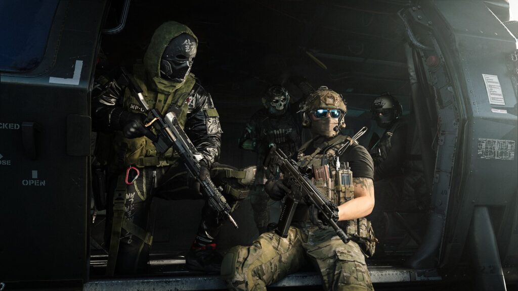 Operadores armados e mascarados sentados na porta aberta de um helicóptero em imagem oficial de Modern Warfare 4