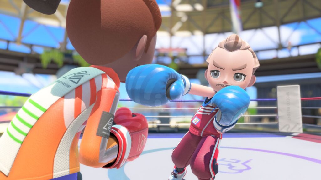 Duelo de boxe no ringue aberto do Spocco Resort: Sportsmate de pompadour desfere um soco com luva azul