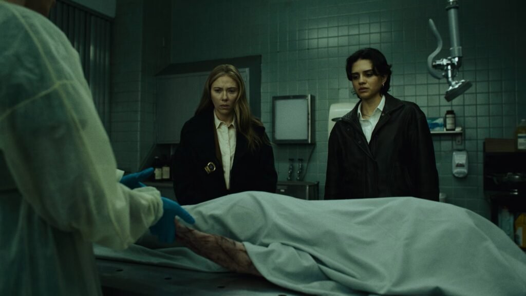 Scarlett Johansson e uma colega diante de um corpo coberto num necrotério em O Exorcista: Mártires