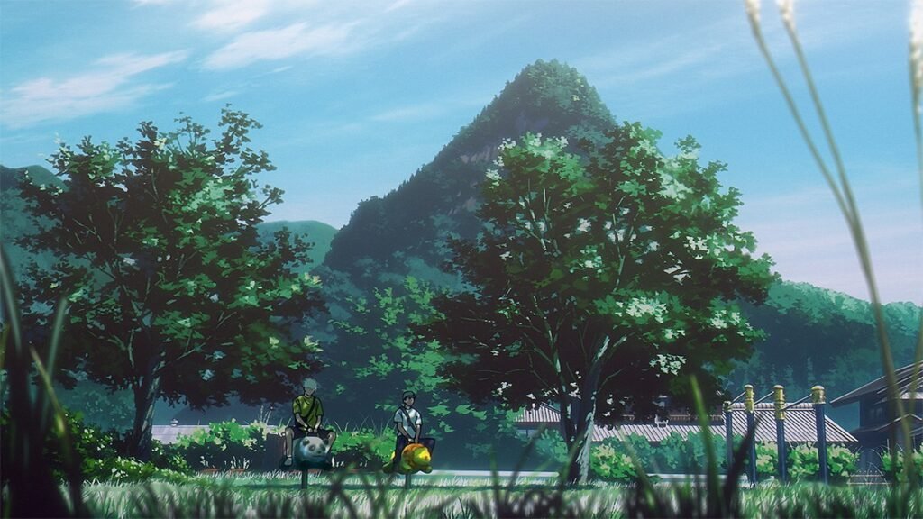 A vila cercada de árvores com a montanha ao fundo, sob céu de verão, em cena do episódio 12 do anime