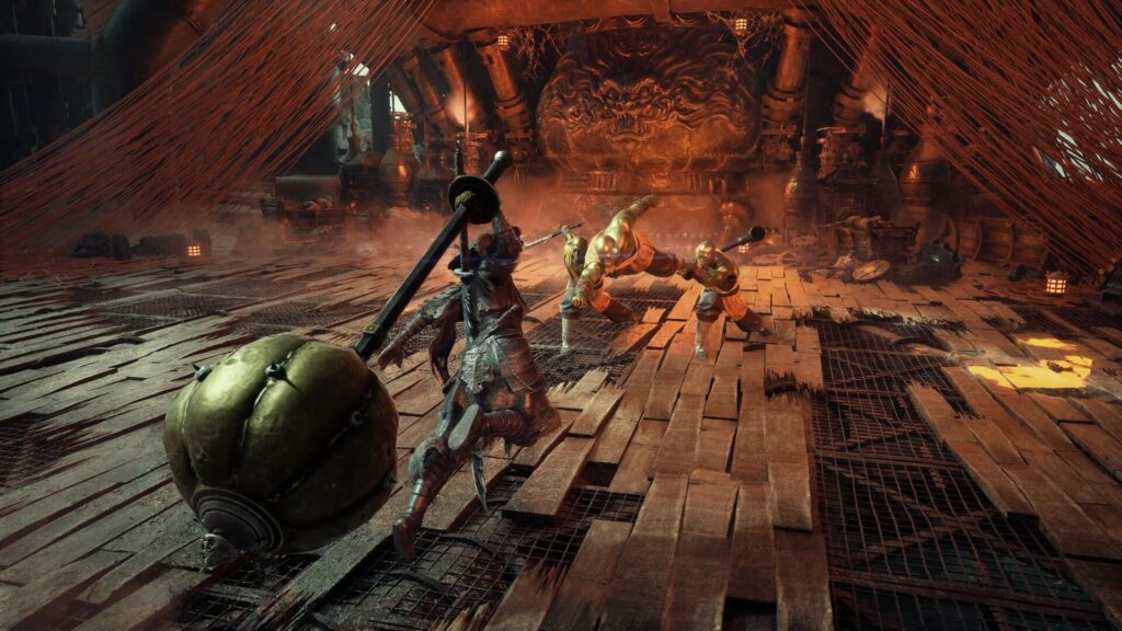Soul gira um martelo gigante contra três monges de pele dourada numa arena de tábuas cercada por fios vermelhos, em screenshot oficial de Phantom Blade Zero