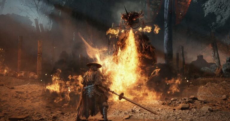 Soul, o protagonista de Phantom Blade Zero, de chapéu de palha e uma lâmina longa na mão, encara um inimigo gigante envolto em chamas numa clareira de terra batida, em screenshot oficial do jogo