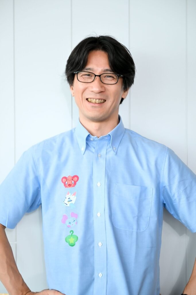 Retrato de Shigeru Ohmori, diretor de Rainy Day, Sunny Girl e de Pokémon Scarlet/Violet, sorrindo de óculos