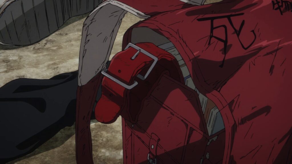 Mochila escolar japonesa vermelha, rasgada e riscada com o ideograma de morte, caída no chão, em cena do trailer do filme de Takopi's Original Sin