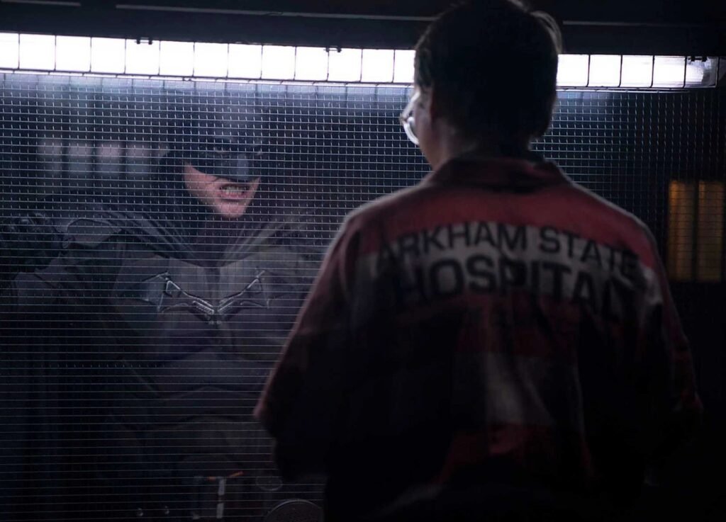 Batman em cena de The Batman (2022), ao lado de um paciente do Hospital Arkham