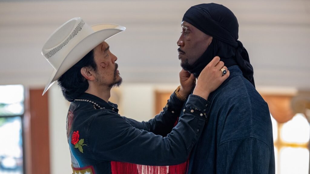 John Cho, de chapéu de caubói branco, segura Mahershala Ali pelo rosto em Your Mother Your Mother Your Mother